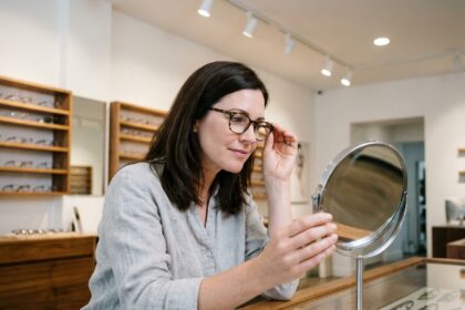 Femme essayant des montures de lunettes chez un opticien moderne, comparant les options disponibles en magasin